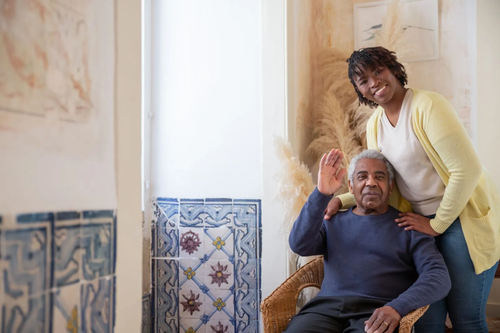 An adult daughter standing beside her father at home. Imagery is illustrative.