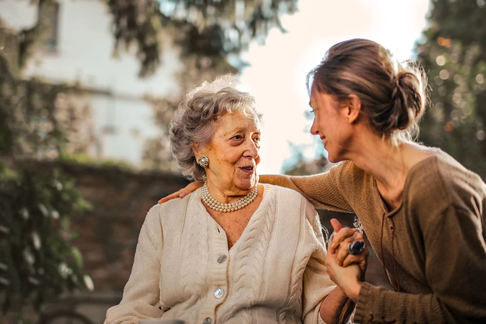 An adult daughter greeting her mother outdoors. Imagery is illustrative.